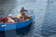 Fisherman At Sunset Reorganizing Nets On His Boat In The Port Of Bari