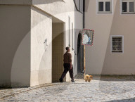 Man Walks A Small Dog Along A Cobblestone Street