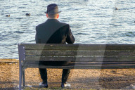 Man In Hat Sitting Alone By Lake