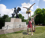 Australia's Head First Acrobats perform the feats of the ancient Greek Gods on the Archilles statue in Hyde Park, London, UK.