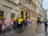 People Queue In Rain At A Famous Schnitzel Restaurant In Vienna