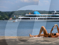 Sunbather Reading By Bavarian Lake Starnberg As Passenger Ship Passes