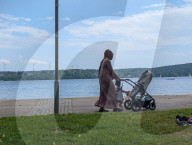 Woman With Child And Stroller By Lake