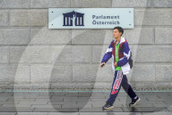 Pedestrian Passes Austrian Parliament Sign