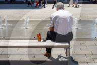 Senior Man Resting By Fountains During Heatwave