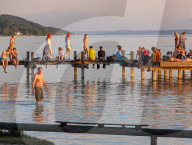 People Enjoy Summer Sunset At Lake