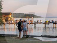 Young Couple And Groups On Jetty At Lake