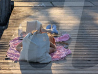 Woman Reading On Jetty In Warm Summer Weather
