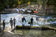 Surfers ride waves on the Eisbach riverin Munich, Germany.