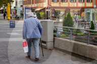 Senior Citizen Walking With Cane And Shopping Bag