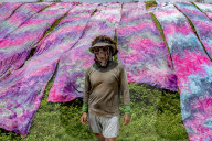 Indonesian Worker Dries Colored Batik Fabric on Riverbank in Sukoharjo