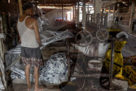 Indonesian Worker Dries Colored Batik Fabric on Riverbank in Sukoharjo