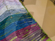 Indonesian Worker Dries Colored Batik Fabric on Riverbank in Sukoharjo