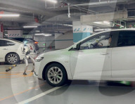 Humanoid robot  pulls car across indoor lot