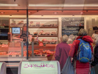 Customers Queue At Gourmet Butcher Meat Stall On Market