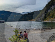 Two Women Rest On The Shore Of Lake