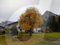 Tyrolean Village Houses And Autumn Foliage Against Zugspitze Massif Backdrop In Biberwier