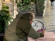 Senior Man Uses Smartphone At Outdoor Cafe In Italy