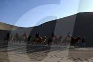 Tourists On Camels At Mingsha Mountain and Crescent Spring Scenic Area - China