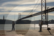 Daily Life Along Lisbon’s Riverside As Locals Fish Beneath The 25 De Abril Bridge