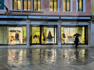 Shoppers Pass Prada Luxury Storefront On Rainy Day