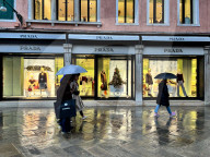 Shoppers Pass Prada Luxury Storefront On Rainy Day
