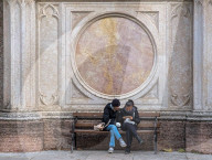 Young Women Use Smartphone On Bench By Marble Facade