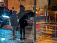 Children Wait To Cross Street In Heavy Rain And Darkness