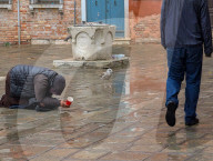 Woman Begging On Wet Pavement During Rain