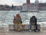 People And Dog Rest On Seawall Bench With Venice Skyline View